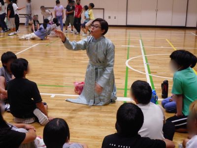 子どもたちの輪に入り遊びの説明をしている講師