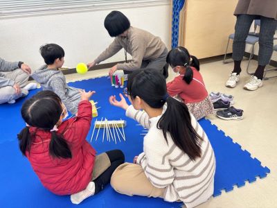 ベトナムの遊びを体験する子どもたちと講師（右手前）の写真