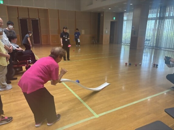 ボッチャ体験においてランプ（競技用補助具）でボールを投げる女性