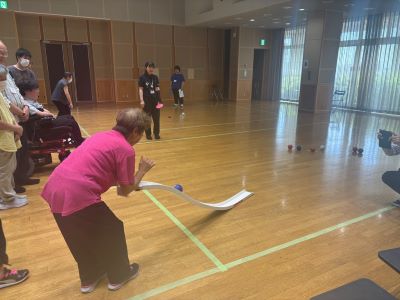 ボッチャ体験においてランプ（競技用補助具）でボールを投げる女性