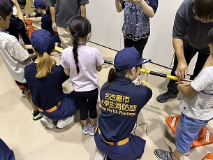 写真:大学生消防団員が結びを教える様子