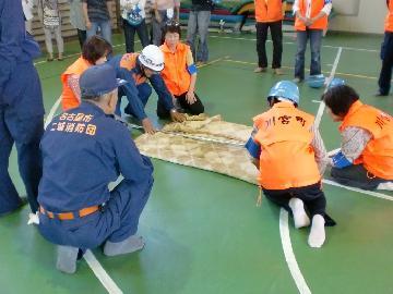 写真:毛布と物干し竿で担架の作成方法を学んでいます