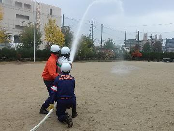 写真:消防団員が補助し、市民の方が放水体験をしています