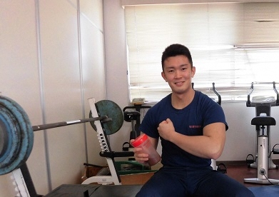 写真:トレーニングルームで腕の筋肉を見せつける消防官