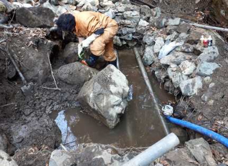 写真:地震により倒壊した水源沈砂地。人が作業を行っている。