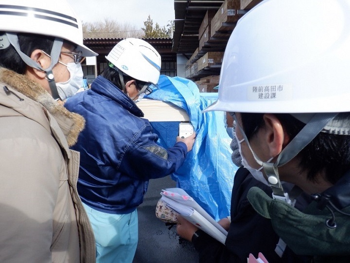 写真:木材の検査の様子。複数人で検査を行っている。