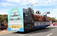 フロート車の上からおもてなし武将隊が手を振っている写真