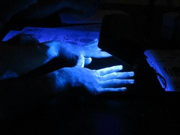 手洗いで洗いにくいところが蛍光で光って見える手の写真