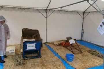 写真:テントの中に、脱穀機や千歯などの農機具が並ぶ様子