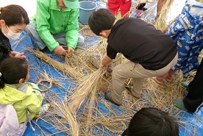 写真:参加者の皆さんが脱穀した後の稲わらで、縄をなう体験をしている様子