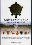 国史跡志段味古墳群ガイドブックの表紙の写真です。志段味古墳群のある上志段味の風景の写真です。その上に、古墳から出土した鏡や埴輪の写真が載っています。