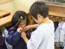 年長児が小さい子の着替えを手伝っている写真