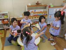 みんなで人形でおままごとをしている写真