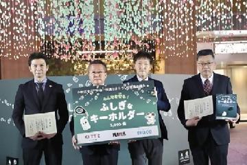 写真:ライトダウンクリスマスツリーの前で、寄贈品の目録と感謝状を披露