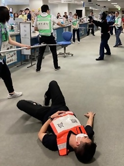 写真：不審者に刺されて倒れる職員役の男性