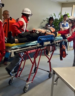 写真：負傷して担架で運ばれる職員役の男性