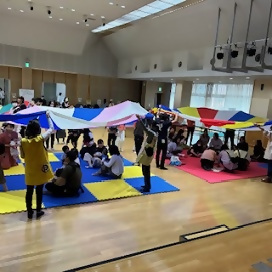 写真：パラバルーンの下で円くなって座る親子さんたち