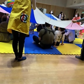 写真：パラバルーンをかぶせられる親子さんたち