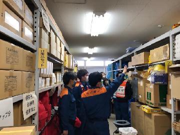 写真：防災倉庫の中で備品の位置などを確認しているところ