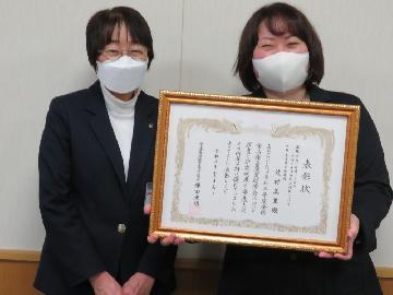 写真：頂いた表彰状を持ち笑顔の職員