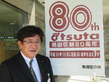 写真：熱田区長（区制80周年ポスター前にて）