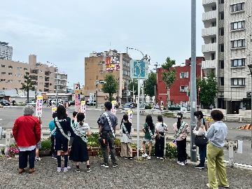 写真:区役所前交差点で、サイン板を掲げて交通安全を呼びかける様子です
