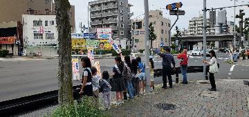 写真:区役所前交差点で、サイン板を掲げて交通安全を呼びかける様子です。