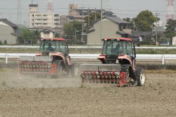 写真:並んで直播作業を行う2台のトラクター
