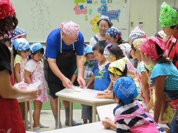 写真：先生がごはんのつぶし方を参加者に説明する様子