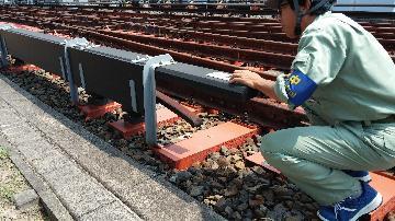 写真：防護カバーに手をついて、高電圧が通った危険箇所を説明する整備員さん