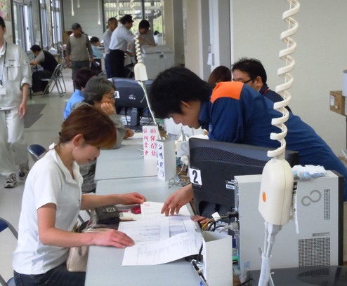 名古屋市の防災服を着て窓口に立つ稲元さんの写真