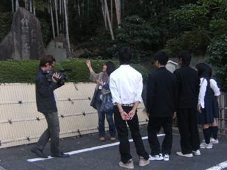 写真:高校生がボランティアガイドの説明を聞く場面の撮影