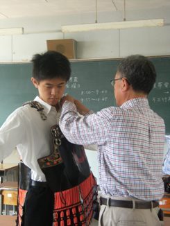 写真:甲冑を着つけてもらう武将役の高校生
