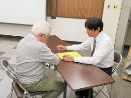 写真：令和元年度天白区コミュニティ交流会　チラシを持参して講師からアドバイスを受ける様子