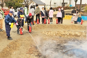 写真：消火器でどんど焼きの火を消す子どもたち