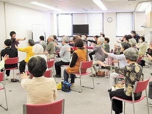 写真：在宅サービスセンターで椅子に腰かけて運動する参加者たち