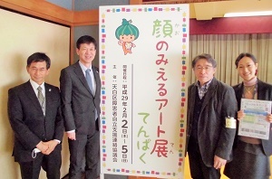 写真：展覧会の看板の横で並んでいる区長ら