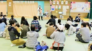 写真：赤ちゃんコーナーで座って話を聞く親子ら