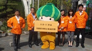 写真：児童虐待防止月間のカードを揚げるかぼっちと職員一同