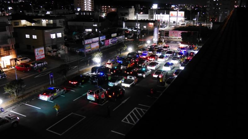 写真：駐車場から出発する区内の青色防犯パトロール車両の列