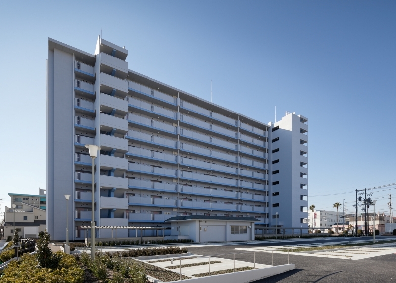 写真：北面廊下側の俯瞰的外観。手前に平屋建ての集会所がある。