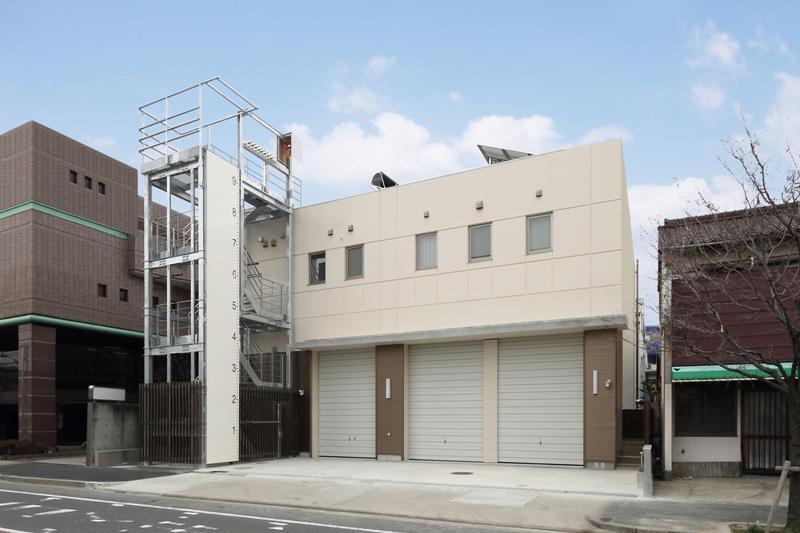 写真：前面道路からの全景。1階は車庫で左側に訓練用階段及び屋上に太陽光パネルが見える。