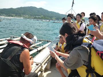 写真:漁船に乗り、養殖されているいかだの見学風景