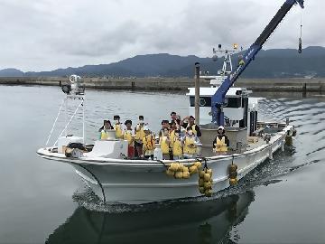 写真:漁船に乗り養殖いかだを見学する様子