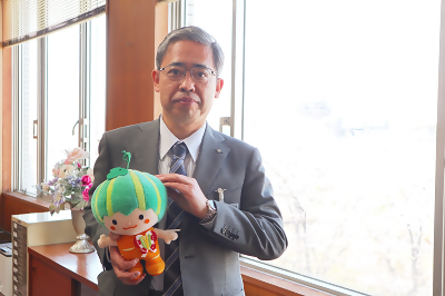 写真：区長室でかぼっちのぬいぐるみを手にする区長