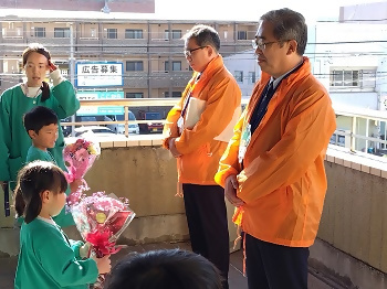 写真：子どもたちからの花束を受け取る区長（右）