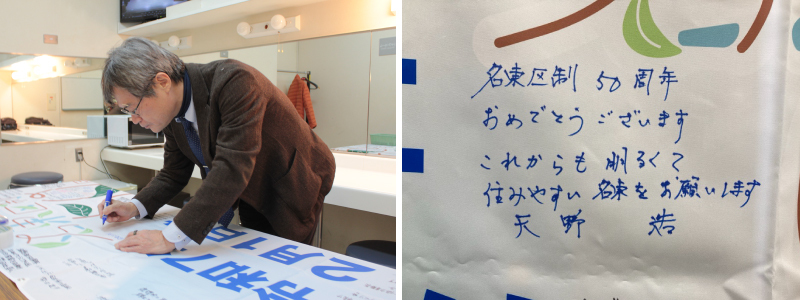 写真：横断幕にメッセージを書く天野教授