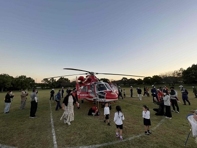 芝生に着陸した消防ヘリを見学する子供達の写真