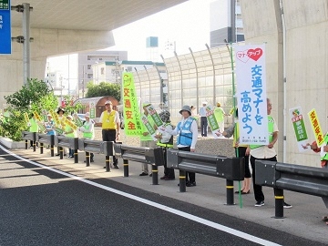 写真:幹線道路沿いで交通安全を呼びかける様子