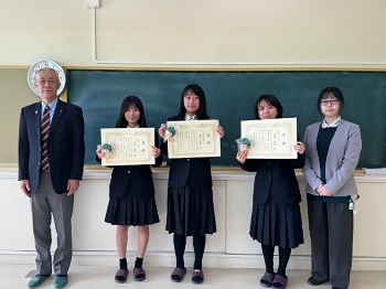 表彰を受けた生徒、鈴木先生、区長の集合写真